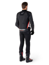 Alpinestars Missile V3 Leather Jacket in Black White Red Fluo, back view on a male rider, featuring Alpinestars branding on the upper and lower back, paired with black pants and motorcycle boots, racing-inspired leather sport jacket.