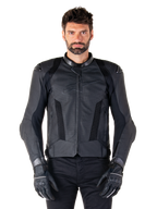 Alpinestars Missile V3 Airflow leren motorjas, zwart, motorracejas, gedragen door een model met zwarte handschoenen en broek, voorzien van geperforeerde leren panelen, mesh ventilatie en externe schouderbeschermers, hoogwaardige leren constructie voor sportief rijden