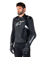 Man die de Alpinestars Missile V3 Airflow leren jas draagt, zwart-witte motorjas, premium geperforeerd leer voor luchtstroom, wit Alpinestars-logo op de borst en mouw, op racen geïnspireerde sportieve pasvorm, gedragen met zwarte handschoenen en broek.