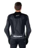 Alpinestars Missile V3 Airflow Leren Jas, zwart en wit, achteraanzicht gedragen door een rijder, met uitgebreide geperforeerde leren panelen, witte zij-accenten, Alpinestars sterlogo op de bovenrug en 'alpinestars RACING AHEAD' branding op de onderrug.