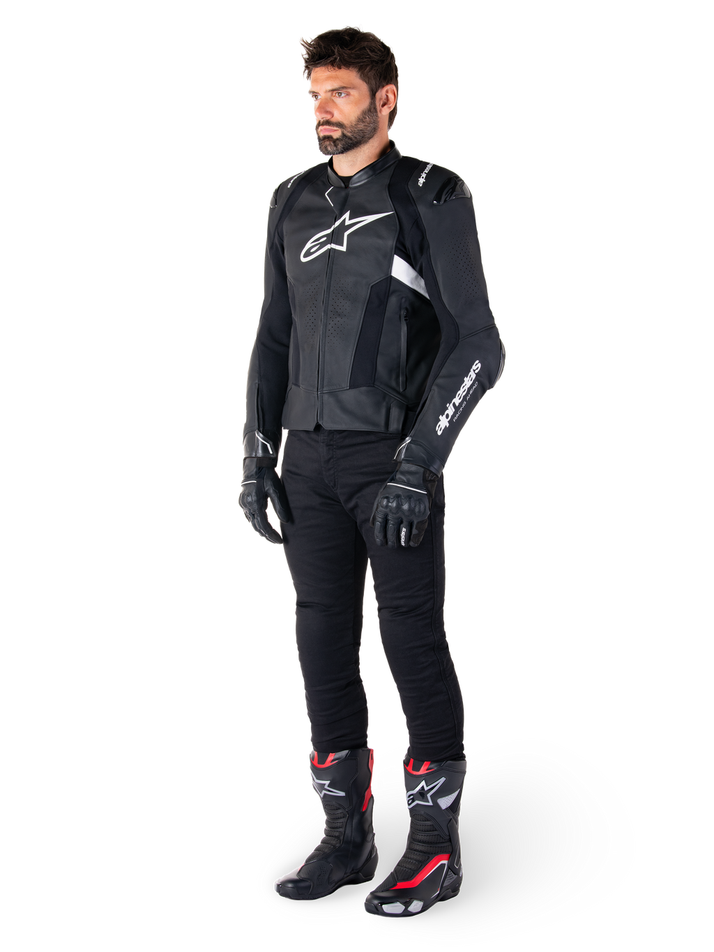 Alpinestars Missile V3 Airflow Leren Jas, zwart en wit, gedragen door een mannelijk model met zwarte motorbroek, zwarte handschoenen en racelaarzen met rode en witte accenten, voorzien van geperforeerd leer en witte logo's, performance motorrace-uitrusting