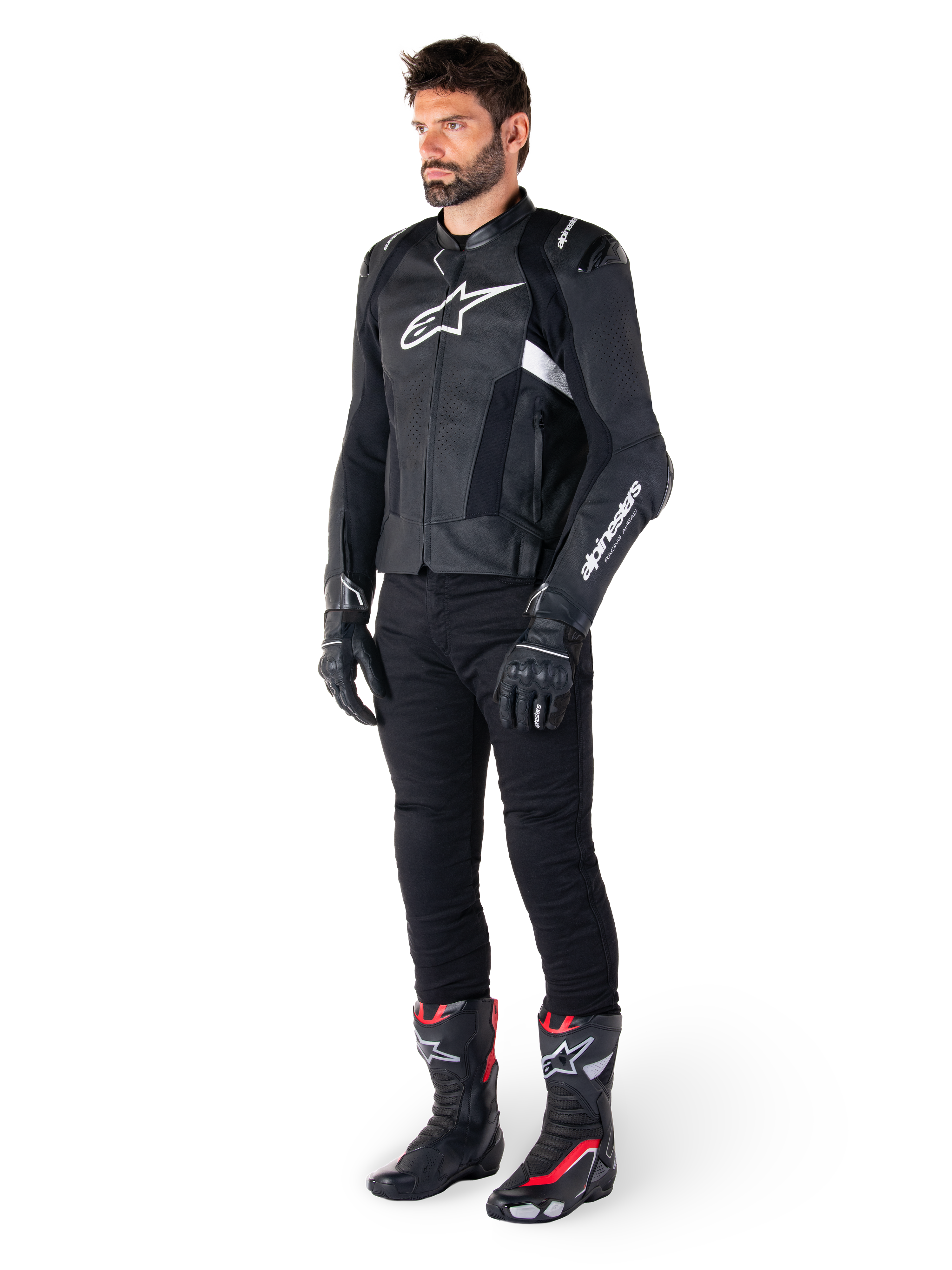 Alpinestars Missile V3 Airflow Leren Jas, zwart en wit, gedragen door een mannelijk model met zwarte motorbroek, zwarte handschoenen en racelaarzen met rode en witte accenten, voorzien van geperforeerd leer en witte logo's, performance motorrace-uitrusting