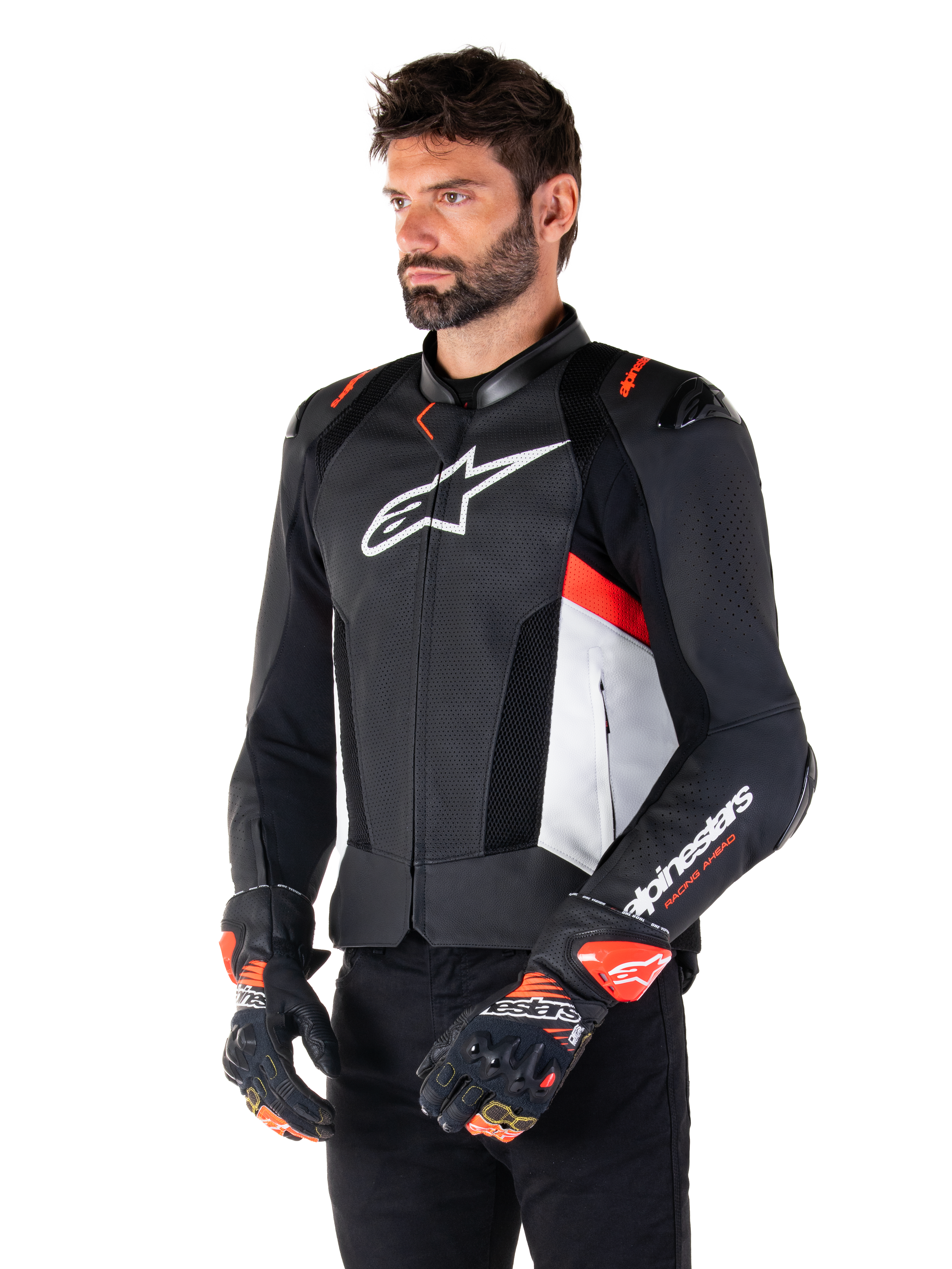 Alpinestars Missile V3 Airflow leren jas, zwart, wit en fluo rood, racing sport motorjas, gedragen door een model met bijpassende handschoenen, voorzien van geperforeerde leren panelen, een groot wit logo op de borst en zwarte schoudersliders.