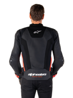 Achteraanzicht van een persoon die de Alpinestars Missile V3 Airflow Leather Jacket in Black White Red Fluo draagt, voorzien van uitgebreide geperforeerde lederen panelen voor ventilatie, een klein Alpinestars-logo op de bovenrug en opvallende 'alpinestars RACING AHEAD' branding aan de onderkant van de rug.