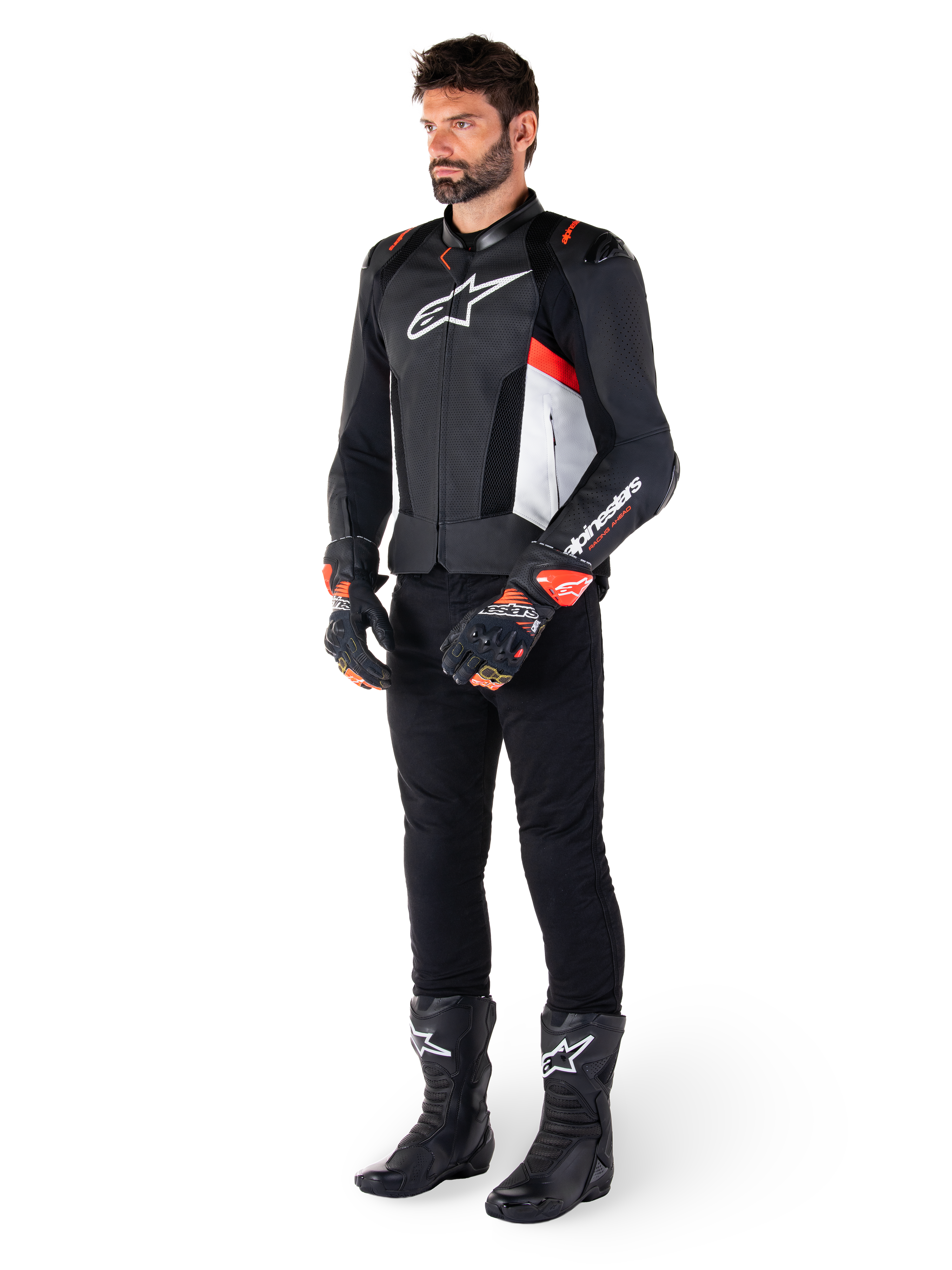 Alpinestars Missile V3 Airflow Leren Jas, zwart wit en rood fluo, gedragen door mannelijk model met zwarte broek, racehandschoenen en laarzen, geperforeerd leer voor ventilatie, wit logo op de borst, premium race- en sportprestaties