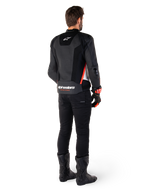 Rijder van achteren gezien met de Alpinestars Missile V3 Airflow leren jas in Black White Red Fluo, gecombineerd met een zwarte broek en zwarte laarzen, voorzien van uitgebreid geperforeerd leer voor ventilatie, DFS schouderprotectie en opvallende Alpinestars branding op de onderrug.