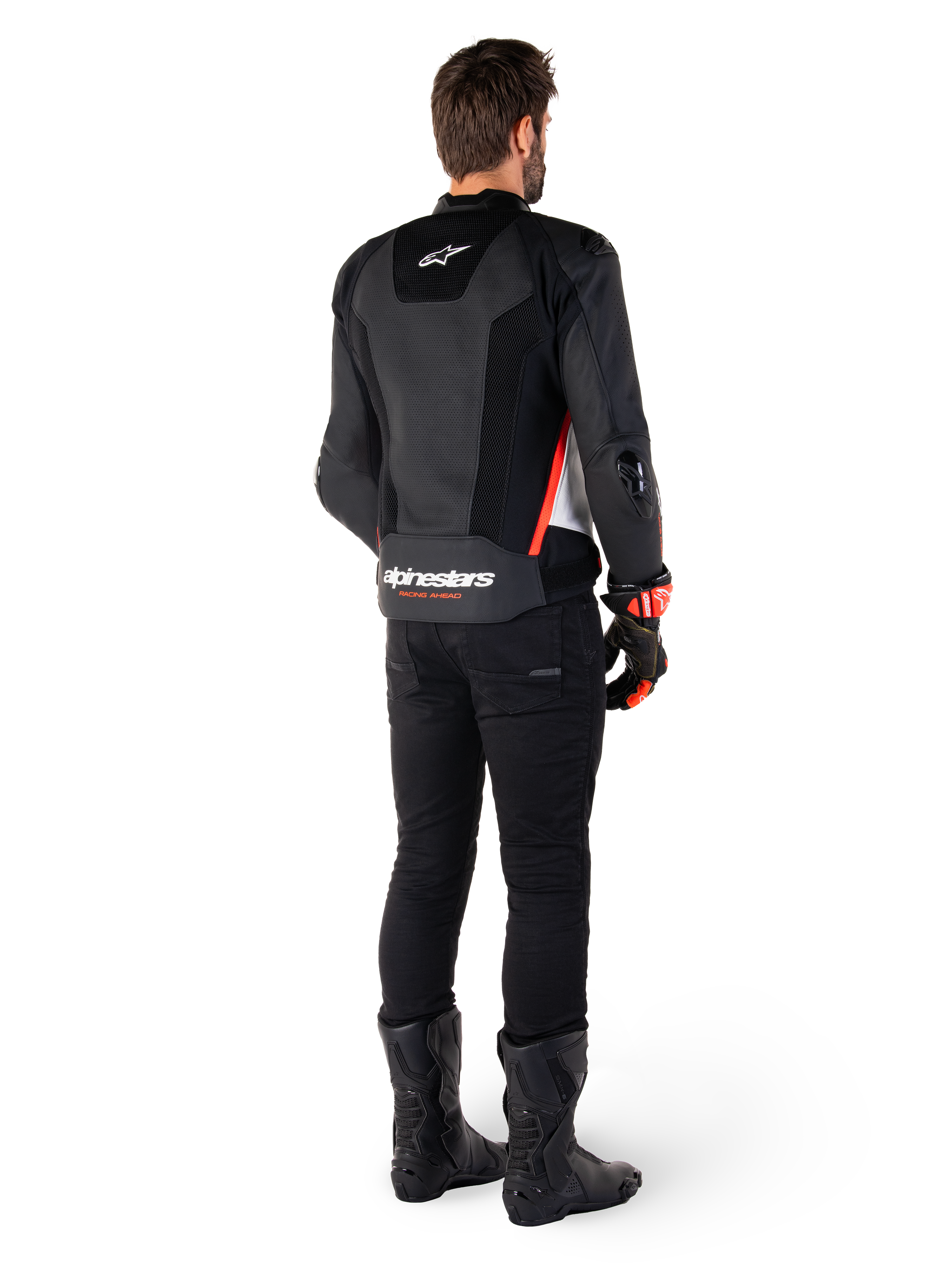Rijder van achteren gezien met de Alpinestars Missile V3 Airflow leren jas in Black White Red Fluo, gecombineerd met een zwarte broek en zwarte laarzen, voorzien van uitgebreid geperforeerd leer voor ventilatie, DFS schouderprotectie en opvallende Alpinestars branding op de onderrug.