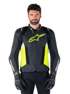 Alpinestars Missile V3 Airflow leren jas, sportieve motorjas, zwart, fluoriserend geel en wit, gedragen door een model met zwarte motorhandschoenen, voorzien van geperforeerd leer op de borst, een opvallend fluorgeel logo en witte merkdetails op de mouwen