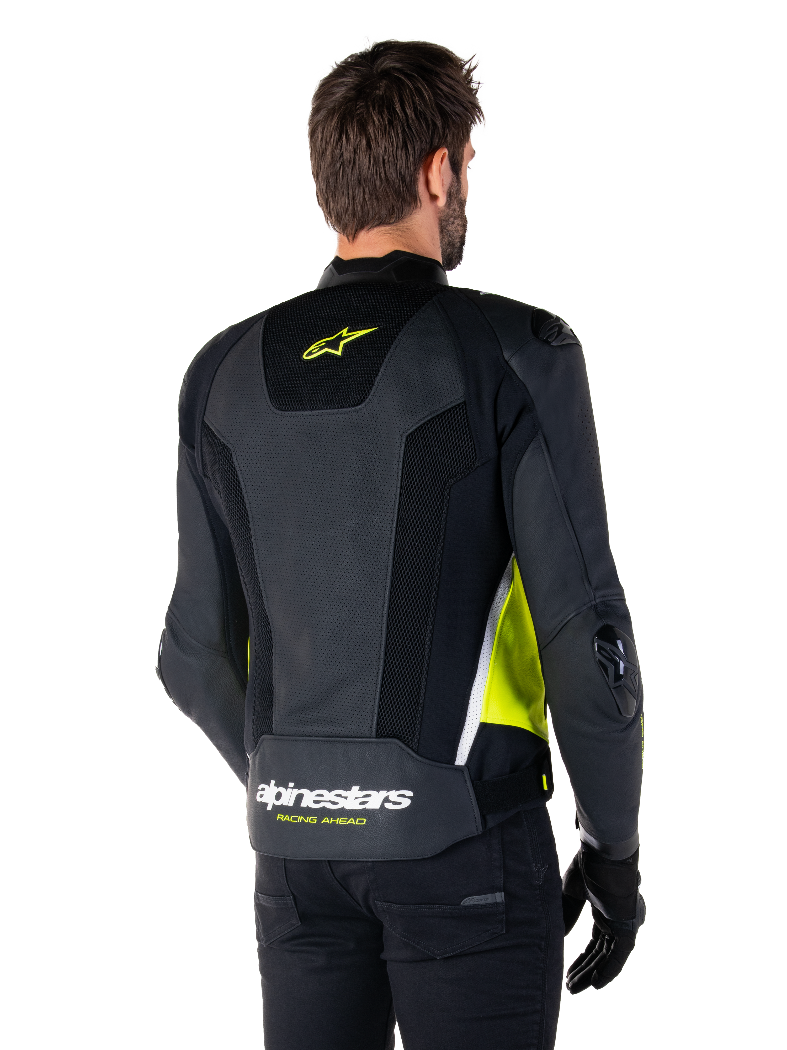 Alpinestars Missile V3 Airflow Leren Jas, achteraanzicht op een mannelijk model, zwart met fluo gele en witte accenten, voorzien van uitgebreide geperforeerde leren en mesh panelen op de rug, met een geel sterlogo en witte 'RACING AHEAD' tekst, gecombineerd met zwarte handschoenen en broek.