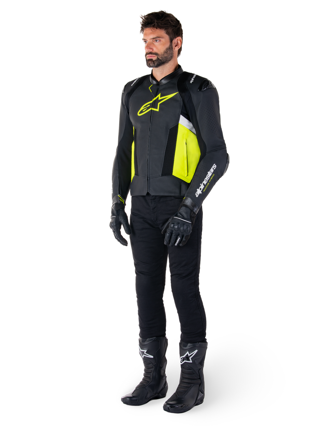 Mannelijk model in de Alpinestars Missile V3 Airflow leren jas, uitgevoerd in zwart, geel fluo en wit, gecombineerd met zwarte motorhandschoenen, broek en laarzen, toont het geperforeerde leren ontwerp en de racing-geïnspireerde esthetiek.