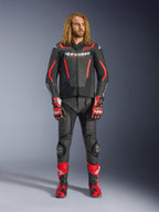 Mannelijk model draagt de Alpinestars GP Force V2 leren jas in Black Red Fluo, gecombineerd met bijpassende leren broek, rode racehandschoenen en rode performance-laarzen, professionele motoruitrusting