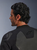 Alpinestars GP Force V2 leren jas, zwart, detailopname van achteren met het zwarte ster-logo op de bovenrug en GP Lite Evo DFS schouderbeschermer, meerpanelige constructie van leer en textiel, studio-opname van het profiel van de rijder en details van de uitrusting