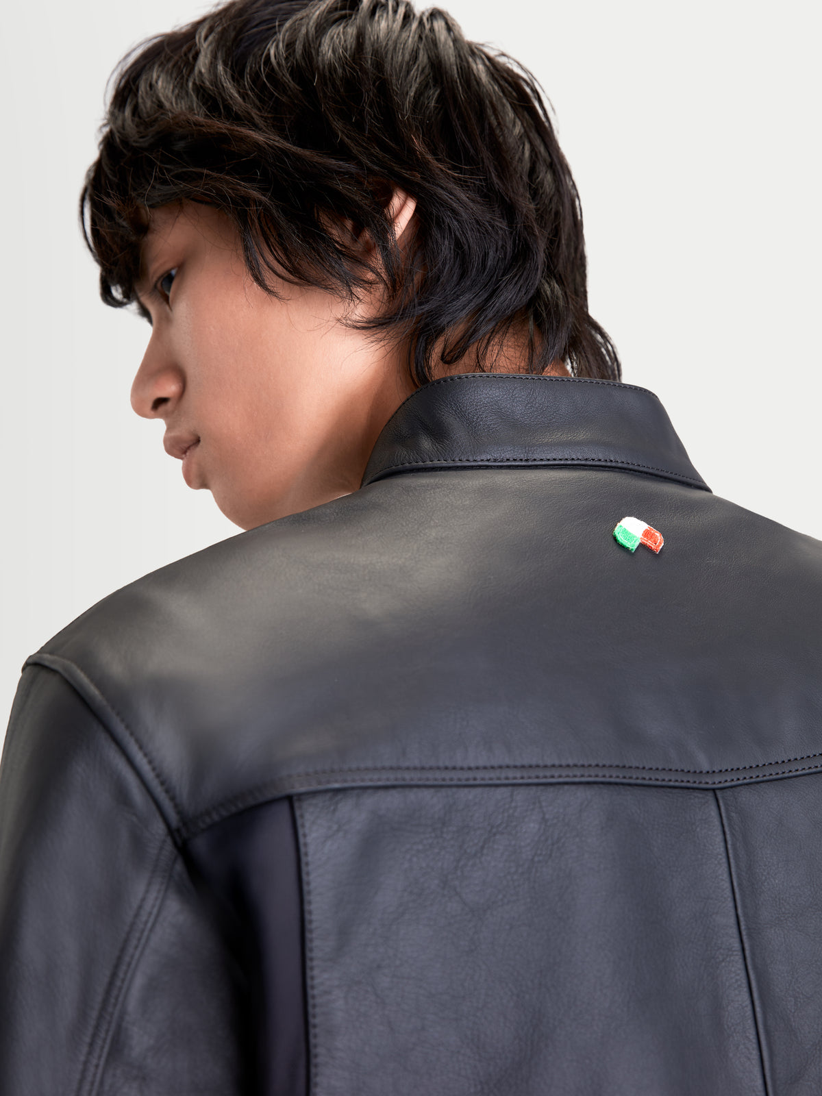 Alpinestars Maver X leren jas, heren urban motorjas in zwart, detailopname van de achterkant met premium rundleerconstructie, biker kraag en Italiaans vlagdetail gedragen door een model