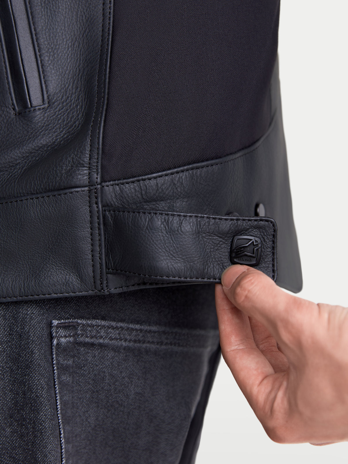 Alpinestars Maver X leren motorjas, urban herenmotorjas, detailopname van de verstelbare drukknopsluiting in de taille in het zwart, premium lederen constructie en stretchinzetstuk