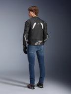 Alpinestars GP Plus R V4 Rideknit leren jas in zwart en wit, achteraanzicht op een model, met witte Alpinestars-branding op de mouwen en een groot sterlogo op de onderrug, gedragen met een blauwe jeans en zwarte motorschoenen, technische motoruitrusting.