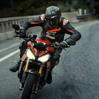 Motorrijder op een rode sportmotor, Alpinestars GP Plus R V4 Rideknit leren jas, zwart met Red Fluo en witte details, voorzien van wit Alpinestars-logo en 'ASTARS'-tekst, gecombineerd met zwarte racehelm en handschoenen, performance motorkleding in actie op de weg.