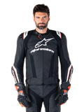 Alpinestars Missile V3 Ignition Leren Jas, zwart met witte en rode accenten, gedragen door een mannelijk model met bijpassende racehandschoenen en broek, sportmotorjas afgeleid van de MotoGP met opvallende branding