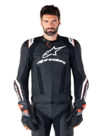 Alpinestars Missile V3 Ignition Leren Jas, zwart met witte en rode accenten, gedragen door een mannelijk model met bijpassende racehandschoenen en broek, sportmotorjas afgeleid van de MotoGP met opvallende branding