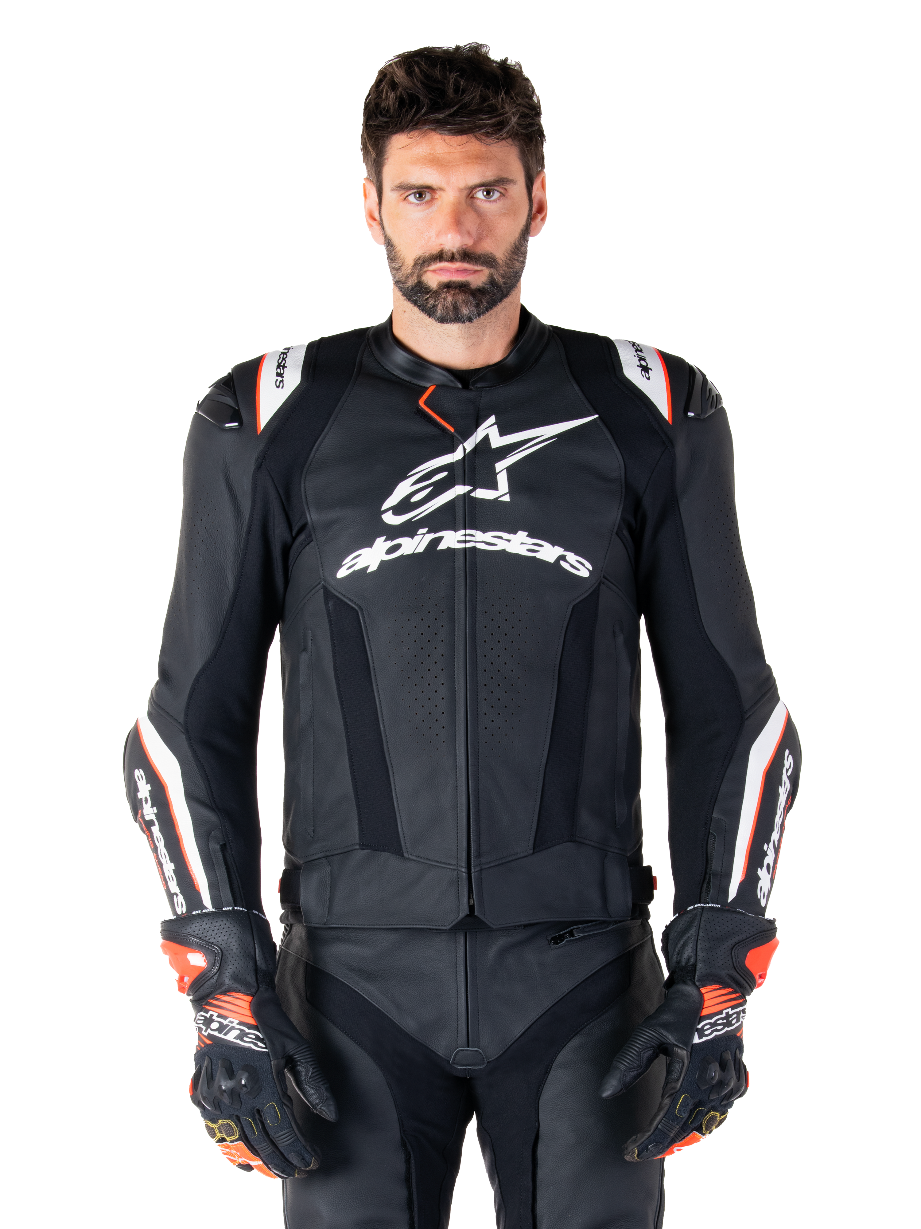 Alpinestars Missile V3 Ignition Leren Jas, zwart met witte en rode accenten, gedragen door een mannelijk model met bijpassende racehandschoenen en broek, sportmotorjas afgeleid van de MotoGP met opvallende branding