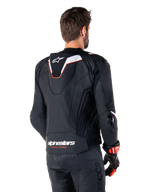 Alpinestars Missile V3 Ignition Leren Jas, achteraanzicht, zwart met witte en rode accenten, voorzien van een slanke sport Aero-hump en Alpinestars-branding, gedragen met bijpassende leren broek en racehandschoenen