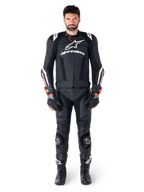Mannelijke motorrijder draagt de Alpinestars Missile V3 Ignition leren jas in het zwart, gecombineerd met een bijpassende leren broek, handschoenen en laarzen, voorzien van witte Alpinestars-branding en rode accenten, ontworpen voor professionele raceprestaties.