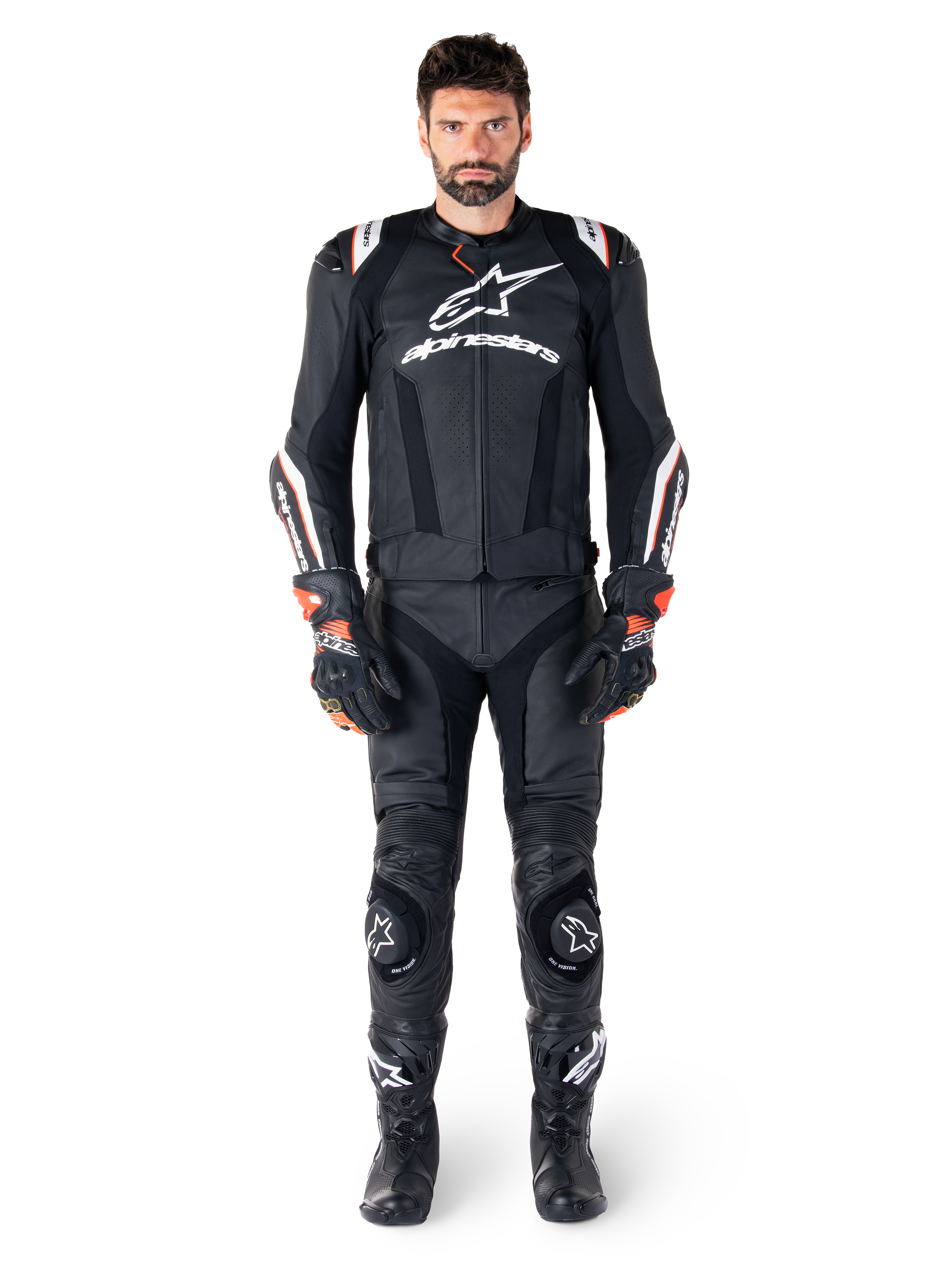 Mannelijke motorrijder draagt de Alpinestars Missile V3 Ignition leren jas in het zwart, gecombineerd met een bijpassende leren broek, handschoenen en laarzen, voorzien van witte Alpinestars-branding en rode accenten, ontworpen voor professionele raceprestaties.