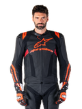 Alpinestars Missile V3 Ignition leren motorjas, racejas, zwart en rood fluo, gedragen met bijpassende racehandschoenen en leren broek, voorzien van geperforeerde ventilatie en opvallende Alpinestars branding, professionele race-uitrusting