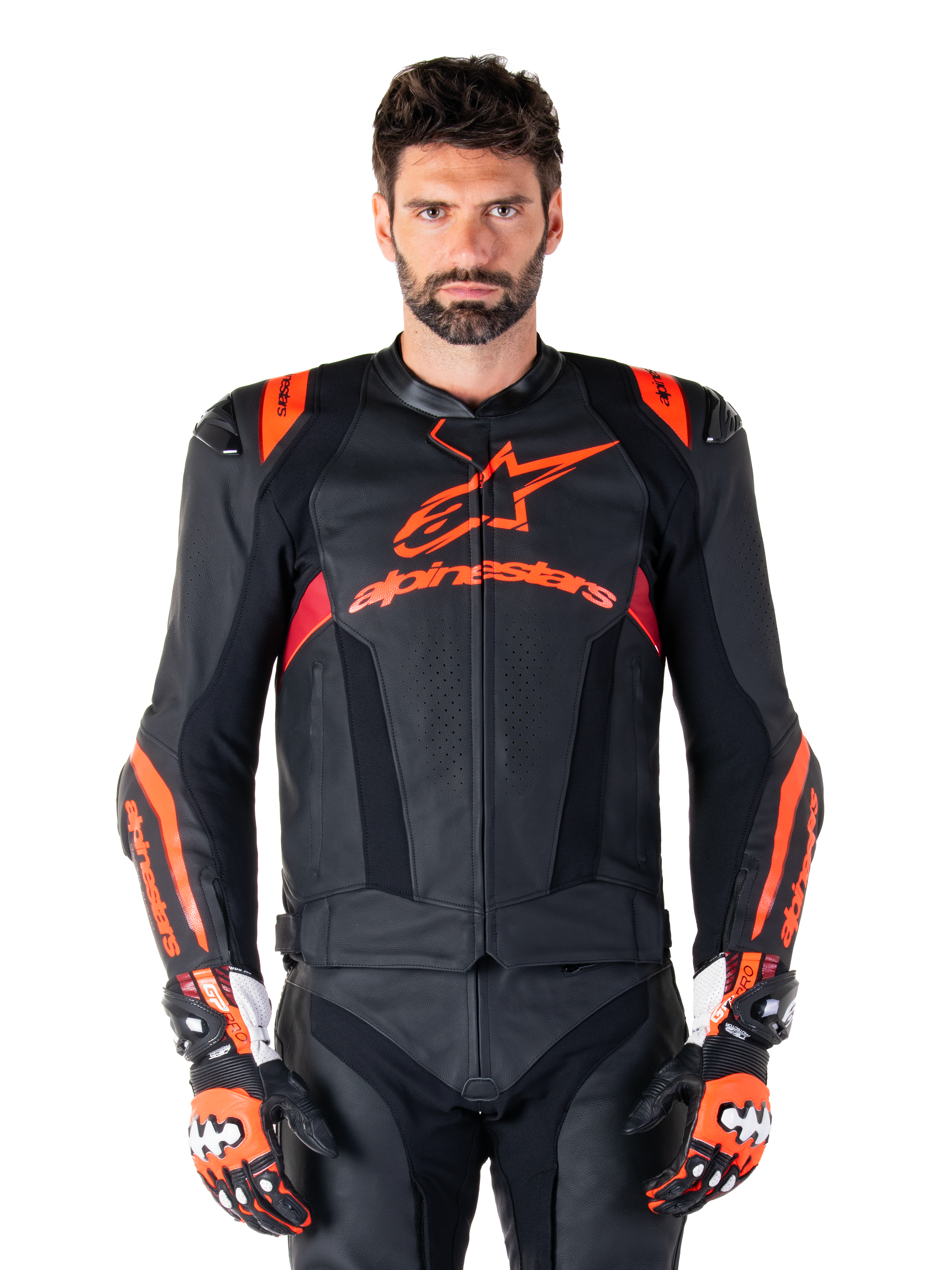 Alpinestars Missile V3 Ignition leren motorjas, racejas, zwart en rood fluo, gedragen met bijpassende racehandschoenen en leren broek, voorzien van geperforeerde ventilatie en opvallende Alpinestars branding, professionele race-uitrusting