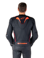 Alpinestars Missile V3 Ignition leren jas, achteraanzicht, zwart met Red Fluo en Dark Red accenten, voorzien van een sportieve aero-hump, Alpinestars-branding op de rug, gedragen met bijpassende zwarte leren motorbroek, hoogwaardige motorrace-uitrusting