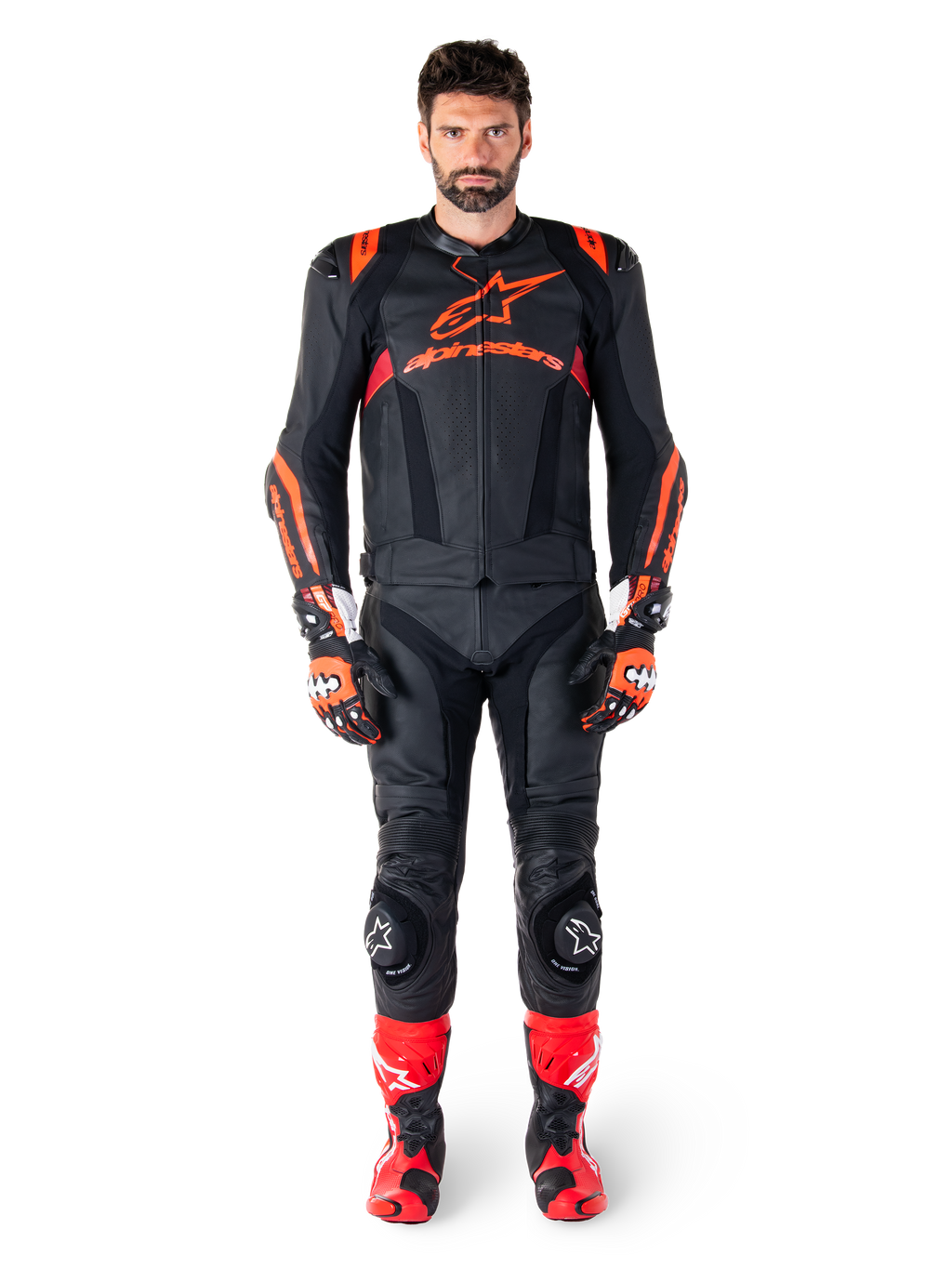 Mannelijk model draagt Alpinestars Missile V3 Ignition leren jas in Black Red Fluo Dark Red, complete motorrace-uitrusting inclusief bijpassende leren broek, racehandschoenen en laarzen, voorzien van opvallende Alpinestars-branding op de borst, naar voren gerichte pose, professionele sport-rijoutfit