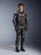Alpinestars GP Force V2 Air Leren Jas in zwart en wit, gedragen door een mannelijke rijder met bijpassende zwarte racebroek, handschoenen en laarzen, voorzien van geperforeerde leren panelen, witte accenten en rood Alpinestars-logo op de borst, sportieve motoruitrusting