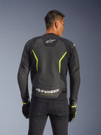 Alpinestars GP Force V2 Air Leren Jas, Zwart en Geel Fluo, achteraanzicht van een mannelijke motorrijder met uitgebreide geperforeerde leren panelen voor ventilatie, wit Alpinestars-logo en gele "Racing Ahead"-tekst op de onderrug, sportieve motoruitrusting voor op de weg.