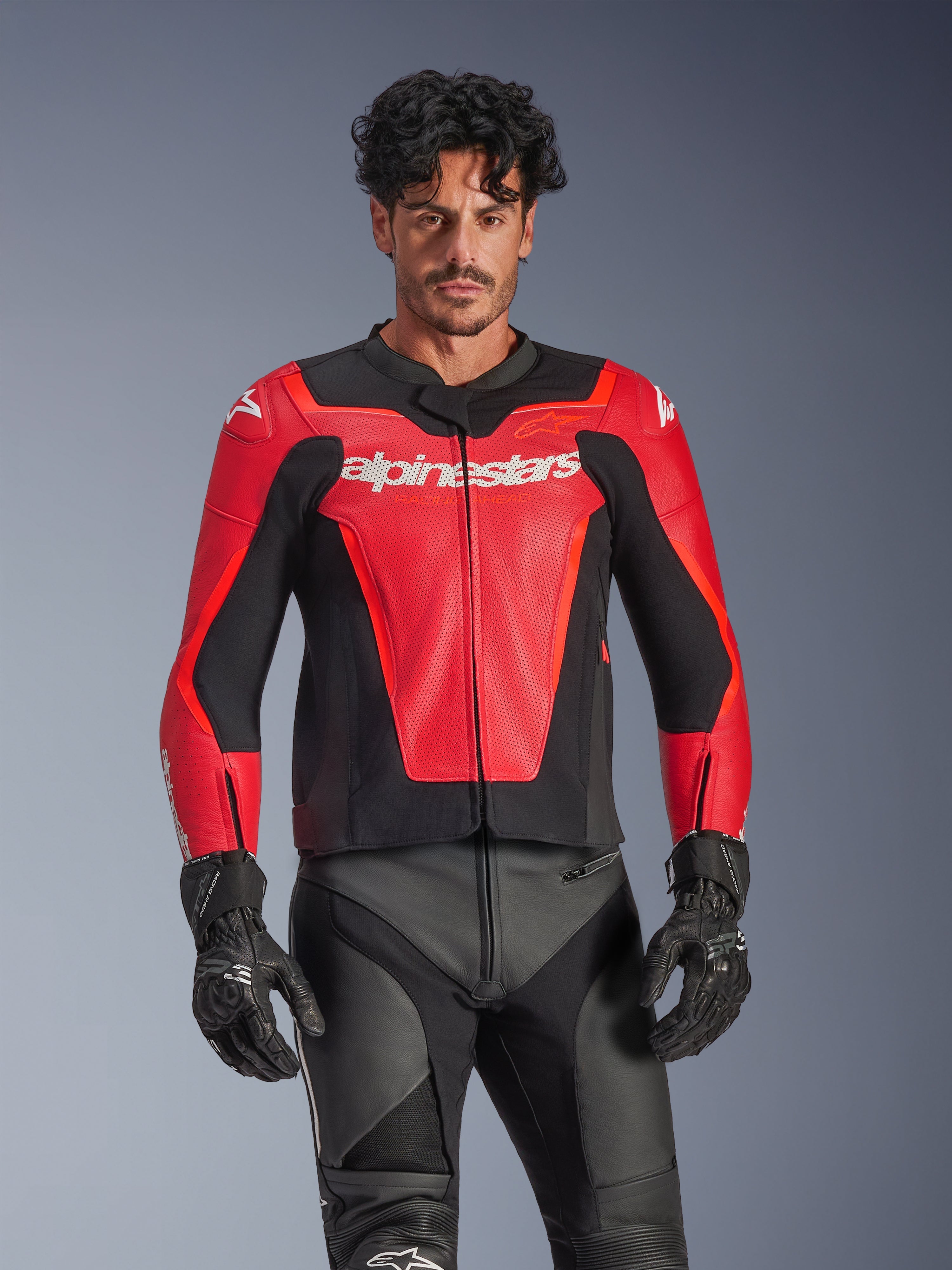 Alpinestars GP Force V2 Air Leather Jacket, rood en zwarte motorjas voor heren, geperforeerde leren constructie met wit Alpinestars-logo, gedragen door een mannelijk model in combinatie met een zwarte motorbroek en handschoenen