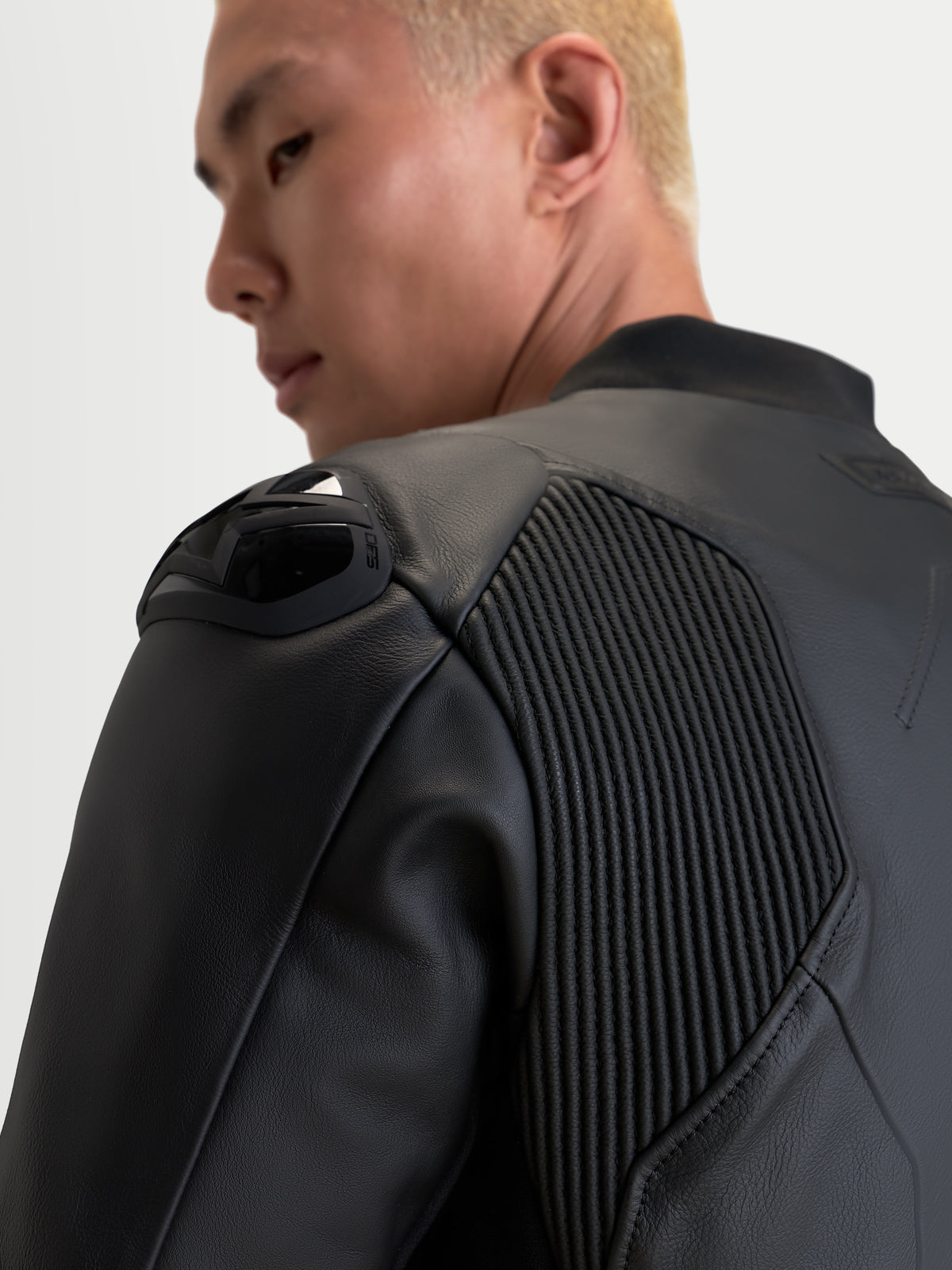Alpinestars Caliber V2 leren jas, zwart, detailopname van de schouderbescherming en accordeon stretchpanelen op een rijder