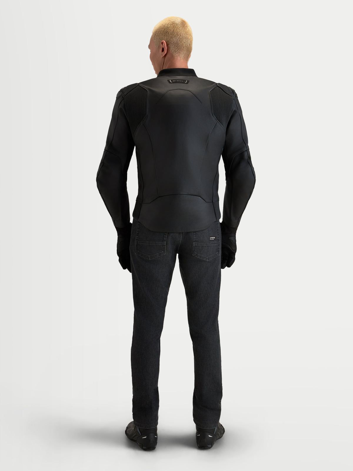 Alpinestars Caliber V2 leren jas, heren motorjas, zwart, volnerf rundlederen constructie met accordeon stretchpanelen, achteraanzicht van een model met sportieve motoruitrusting