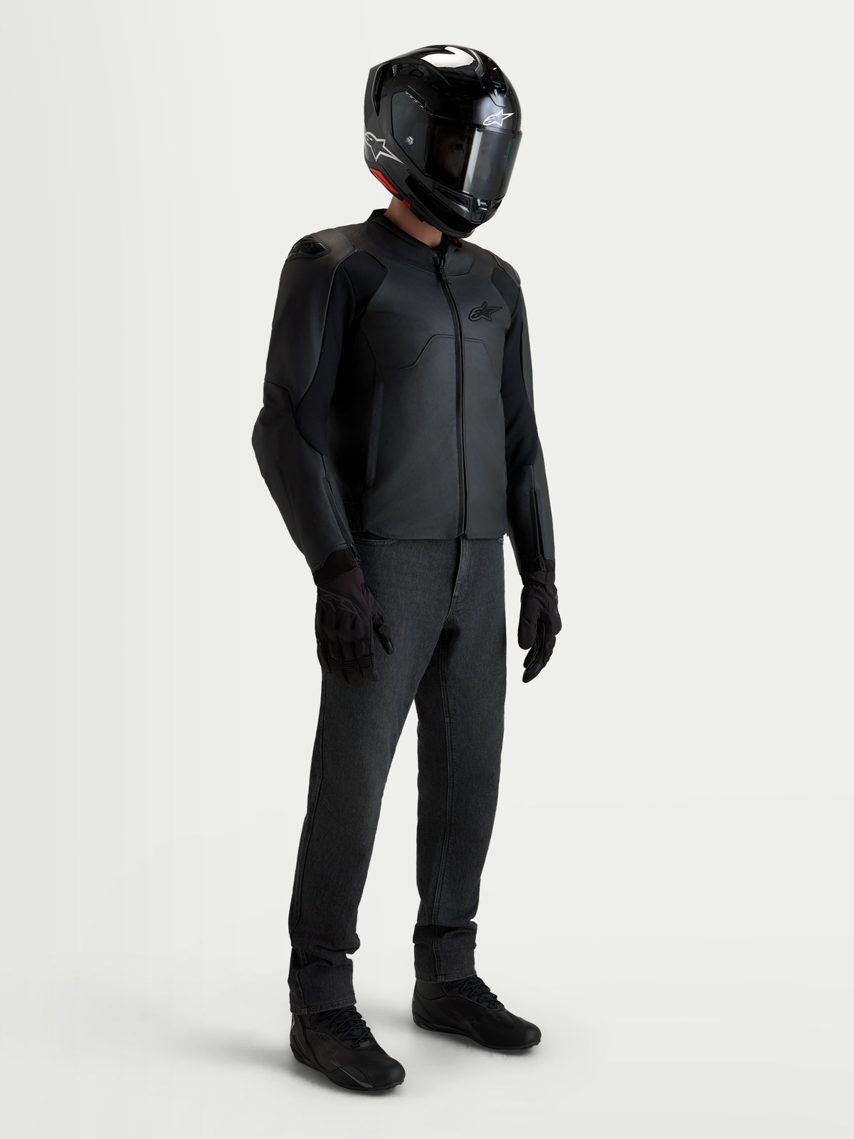 Alpinestars Caliber V 2 leren jas, heren motorjas, zwart, gedragen door een rijder met bijpassende zwarte helm en uitrusting, CE-gecertificeerde AA-bescherming en sportieve pasvorm voor wegritten