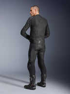 Alpinestars Dusk leren jas, zwart, driekwart achteraanzicht van een model dat een bijpassende leren motorbroek en performance racelaarzen draagt, voorzien van leren accordeon stretchpanelen, zilveren Alpinestars-sterlogo op de onderrug en DUSK-branding op de bovenrug, professionele studio-opname