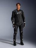 Alpinestars Missile V3 Leren Broek, zwart, gedragen door een mannelijke rijder als onderdeel van een volledige leren motorrace-outfit, voorzien van witte Alpinestars-branding, beschermende kniesliders, racelaarzen en handschoenen.
