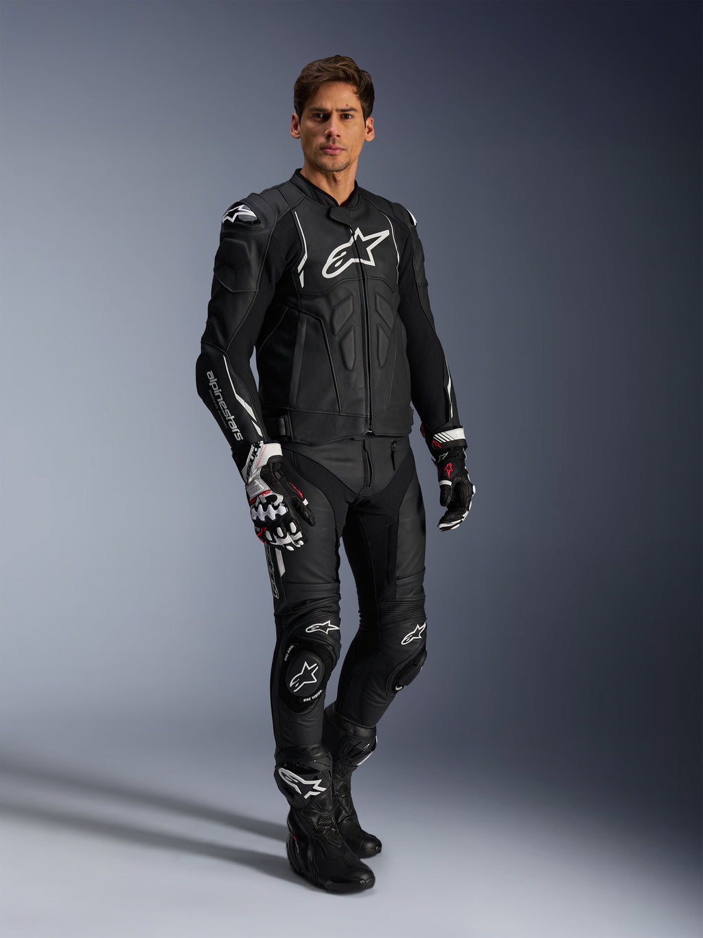 Alpinestars Missile V3 leren broek en bijpassende zwarte leren jas, volledig motorracepak, zwart met witte Alpinestars-branding op de borst en knieën, inclusief professionele racehandschoenen en laarzen, strakke beschermende kleding voor op de weg en het circuit.