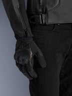 Alpinestars GP Plus V4 Leren Jas, sportieve motorjas, zwart, detailopname van de tailleverstelling en mouwritssluiting, gedragen met zwarte motorhandschoenen, strakke professionele motoruitrusting