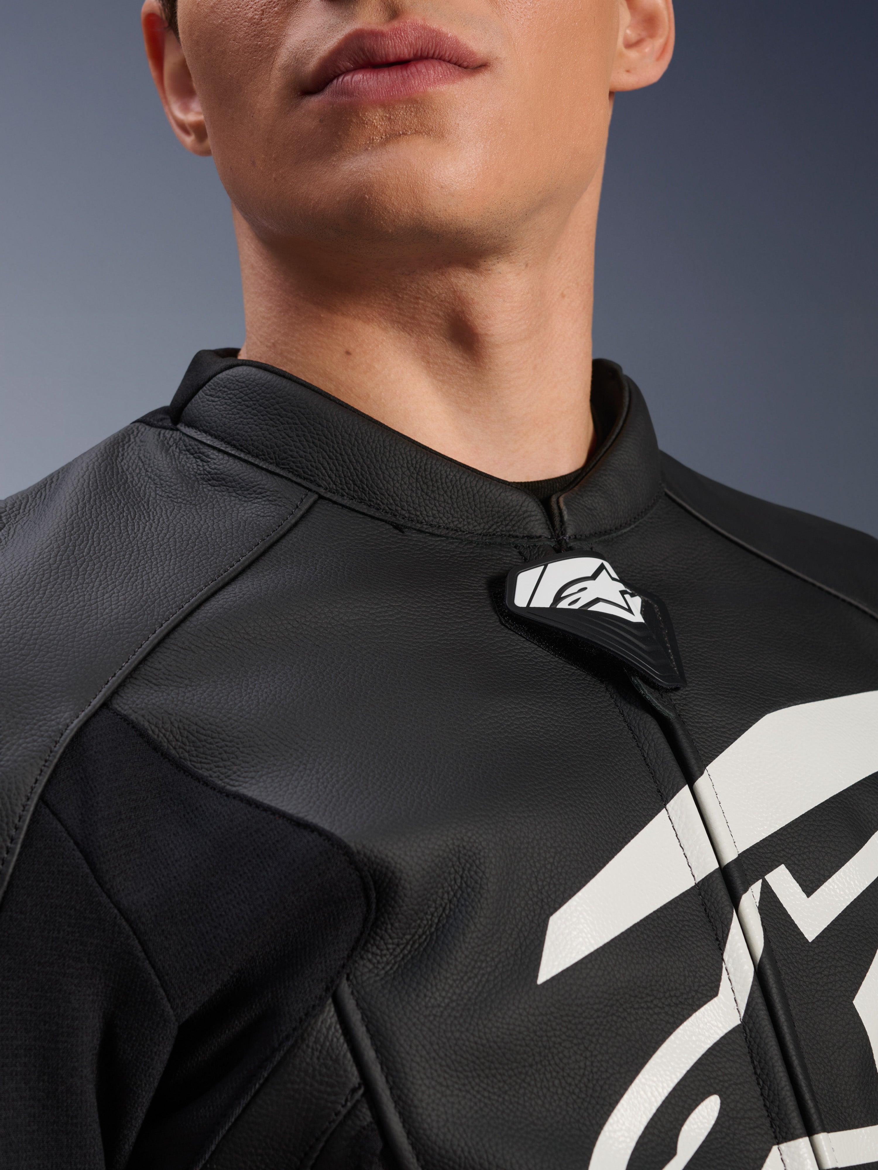 Alpinestars GP Plus V4 Leren Jas, sportmotorjas, zwart en wit, close-up van de kraag van getextureerd leer en Alpinestars logo-tab, witte graphic op de borst, race-afgeleid ontwerp