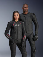Alpinestars Dusk Airflow en Stella Dusk leren jassen, mannelijke en vrouwelijke motorrijders in zwarte leren motorjassen, herenjas met geperforeerd leer voor ventilatie, damesjas met rode accenten en witte logo's, gecombineerd met zwarte motorbroek en handschoenen, sportieve motorrijuitrusting