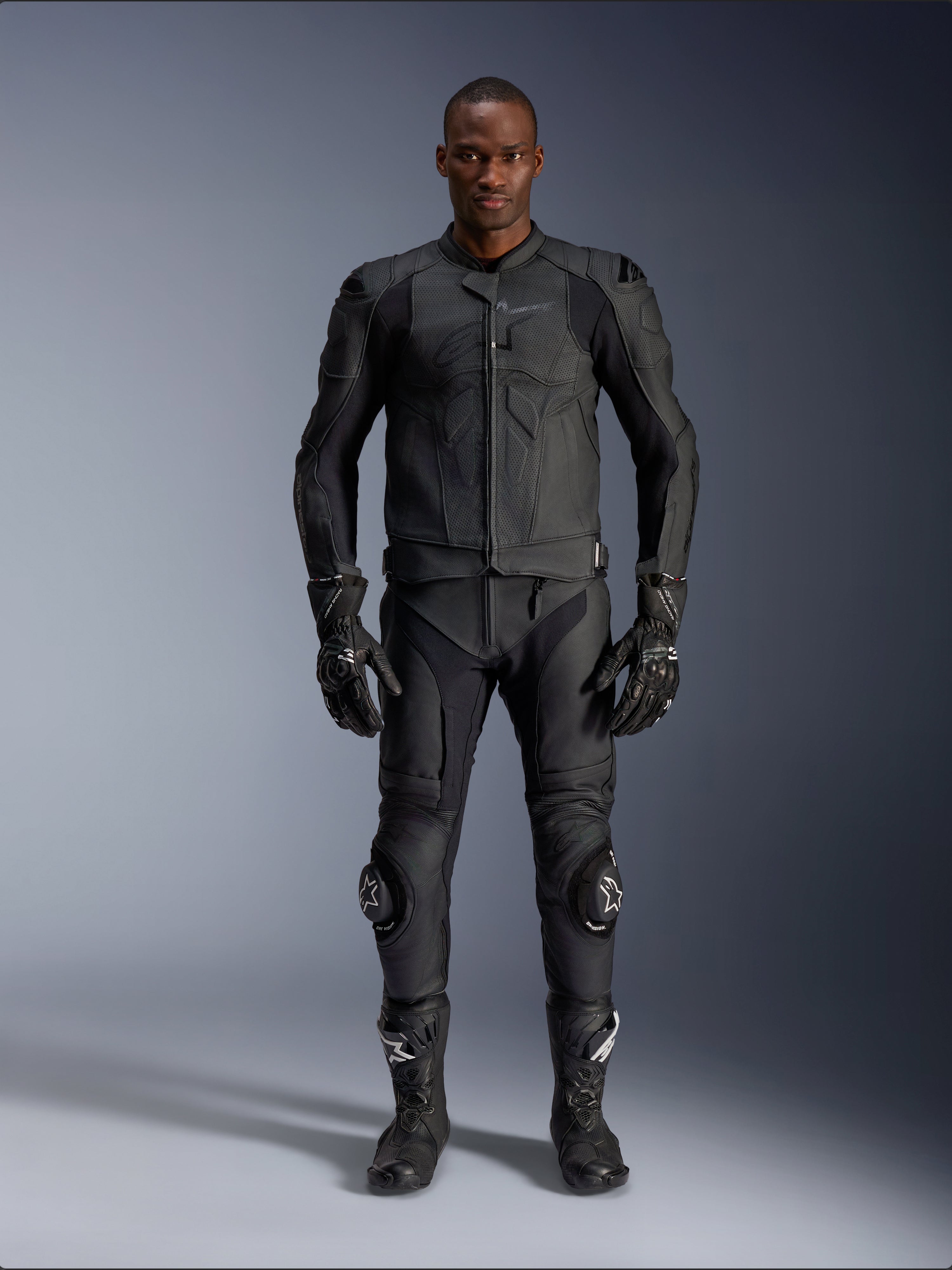Alpinestars Dusk Airflow Leren Jas, zwart, gedragen met bijpassende motorbroek, handschoenen en laarzen, voorzien van geperforeerd leer voor maximale luchtstroom, ergonomisch multi-paneel ontwerp en interne protectie, professionele weg- en sportuitrusting