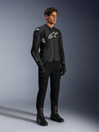 Alpinestars Dusk Airflow Leren Jas, zwart en wit, gedragen met zwarte motorbroek, handschoenen en laarzen, voorzien van geperforeerde leren panelen en witte logo-branding, sportieve road racing stijl.