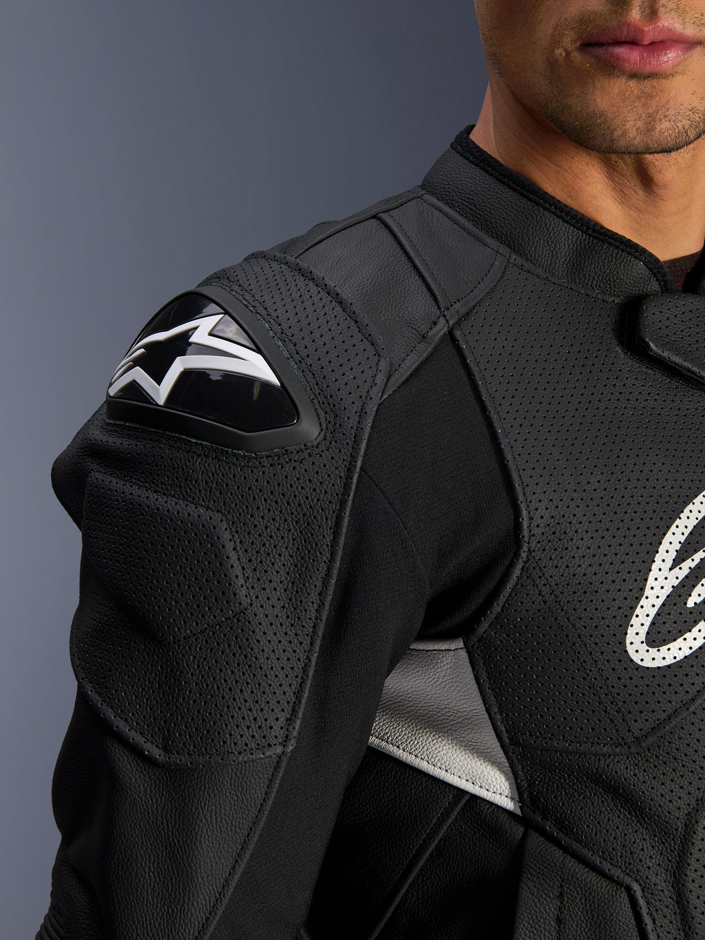 Alpinestars Dusk Airflow Leren Jas, zwart en wit, close-up van de schouder en borst, voorzien van geperforeerd leer voor ventilatie, DFS-schouderbescherming met wit Alpinestars-logo, sportief ontwerp.
