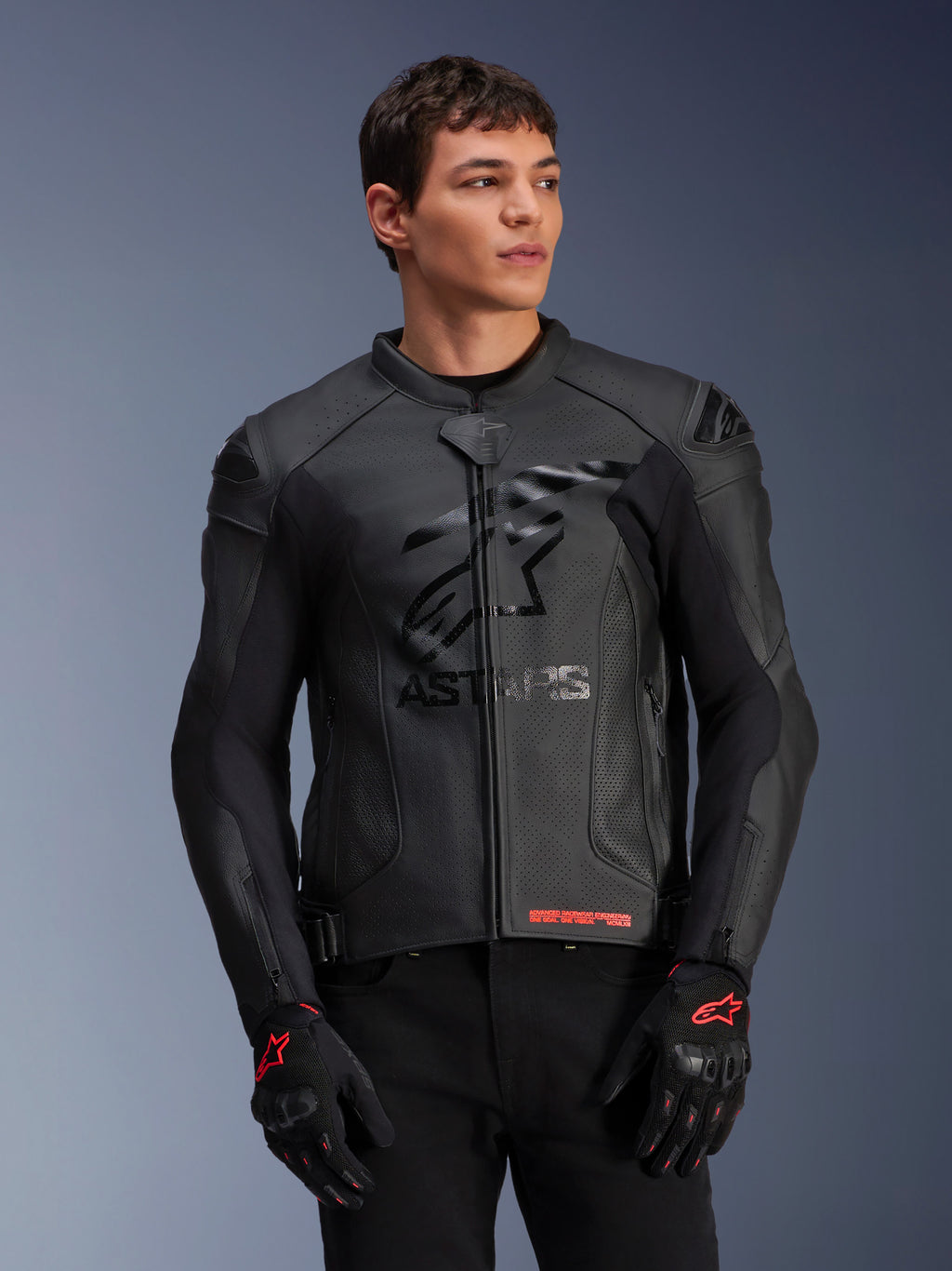 Alpinestars GP Plus R V4 Airflow leren jas, zwarte motorjas met geperforeerd leer, voorzien van prominent ASTARS-logo op de borst en DFS-schouderbescherming, gedragen met zwart-rode handschoenen