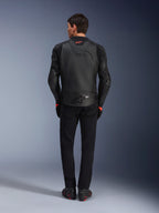 Alpinestars GP Plus R V4 Airflow Leren Jas, zwart, achteraanzicht van motorrijder in volledige uitrusting, voorzien van geperforeerd leer voor ventilatie en rode logo-accenten, gestroomlijnd sport-fit ontwerp, gecombineerd met een zwarte broek en motorlaarzen