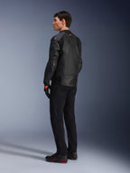 Alpinestars GP Plus R V4 Airflow leren jas, sportieve motorjas voor heren, volledig zwart, driekwart achteraanzicht op een model, voorzien van geperforeerde leren panelen, rood logo op de rug en geïntegreerde schouderbescherming, gedragen met een zwarte broek en motorschoenen