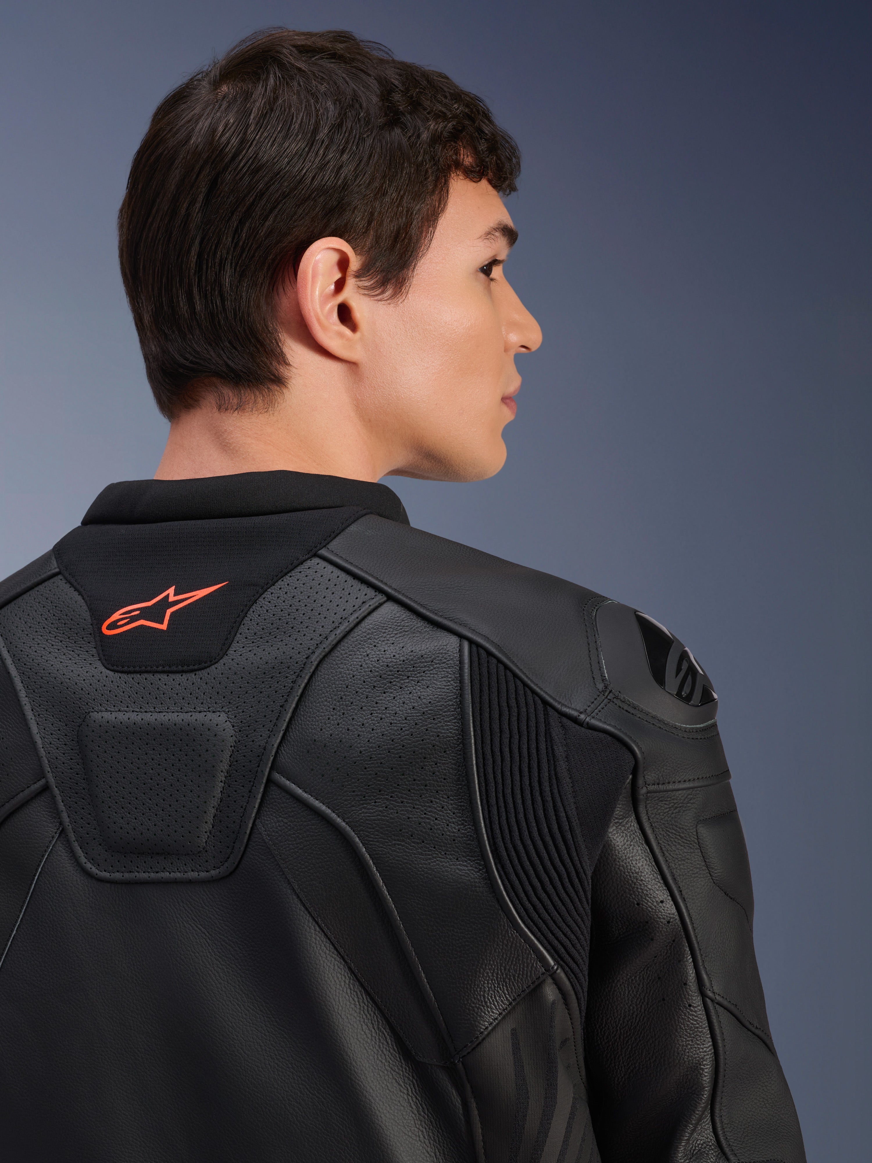 Alpinestars GP Plus R V4 Airflow leren jas, zwart, close-up achteraanzicht op een model, voorzien van geperforeerd leer van racekwaliteit, technische stretchpanelen en een klein oranje Alpinestars-logo op de kraag, professionele motorkleding