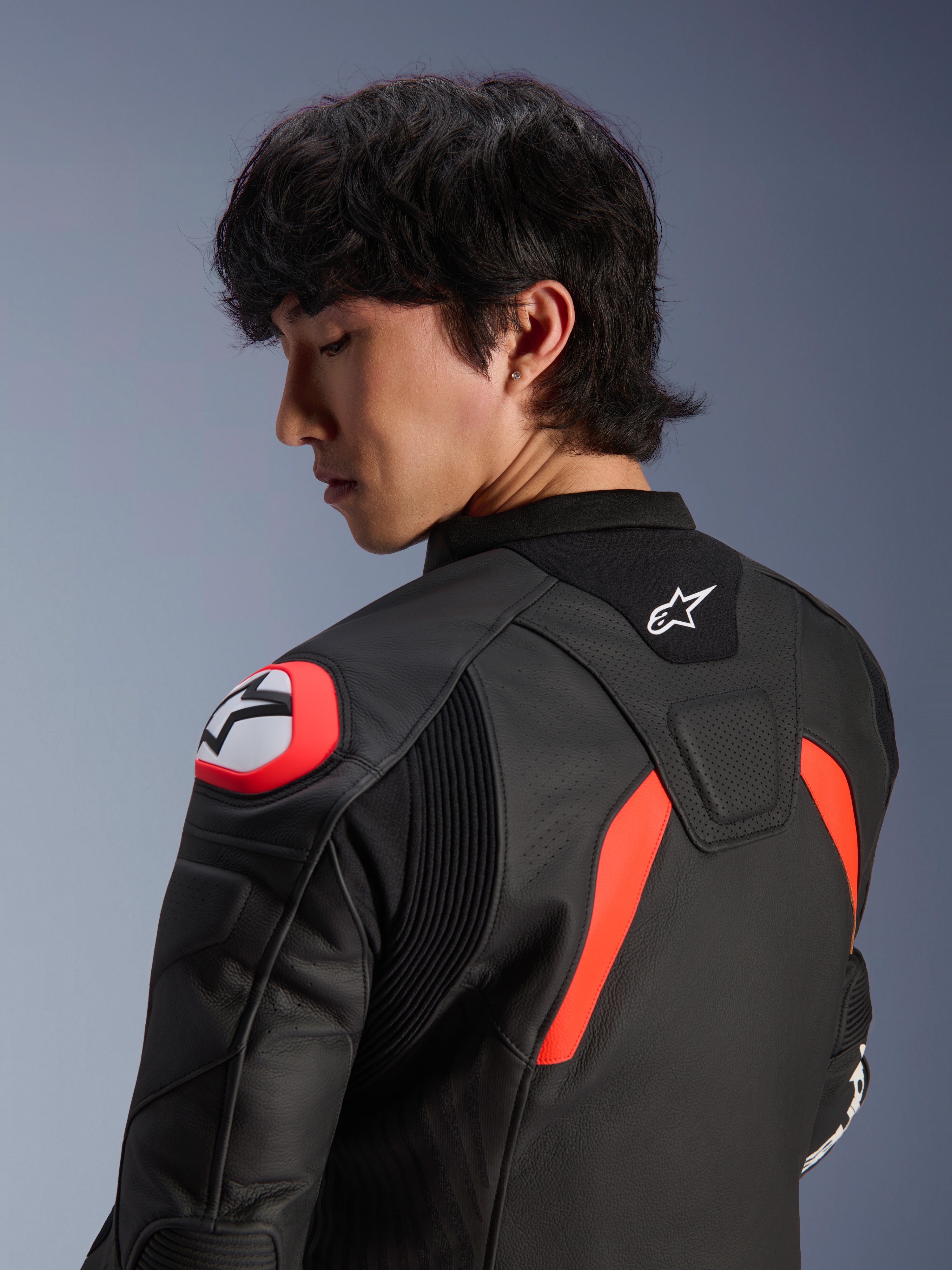 Alpinestars GP Plus R V4 Airflow leren jas, zwart met rood fluo en witte accenten, close-up van de rug en schouder op een model, voorzien van geperforeerde lederen zones, Alpinestars-logo en geïntegreerde schouderbescherming voor motorprestaties.